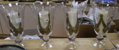 A set of four glass storm shades, with candles height 35cm