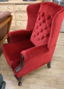 A wing armchair with buttoned red velour upholstery