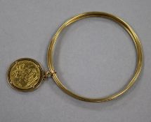 A unmarked triple hoop gold bracelet, hung with an 1885 gold sovereign pendant gross 29.1 grams