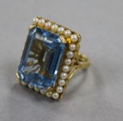An unmarked yellow metal dress ring, set with an aquamarine and pearls size I, gross 14.4 grams