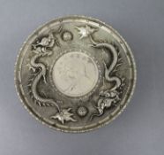 A white metal Chinese scroll dish with coin in centre