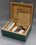 A green stained bird's eye maple humidor containing a selection of cigars