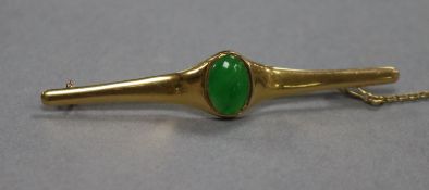 A Chinese yellow metal and jadeite cabochon bar brooch, 62mm.