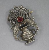 An Art and Crafts white metal and cabochon ruby brooch, modelled as two birds with a vase, 40mm.