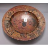 A large circular patinated copper dish, impressed 'S.F.' to foot rim, with wide 'pleated' edge,