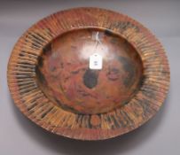 A large circular patinated copper dish, impressed 'S.F.' to foot rim, with wide 'pleated' edge,