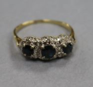 An 18ct gold and three stone sapphire ring, with diamond chip spacers, size R.