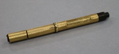 An Edwardian engine turned yellow metal fountain pen, with engraved inscription, 12.6cm.