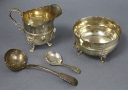 A George V silver cream jug and sugar bowl and a 19th century silver caddy spoon and sauce ladle.