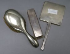 An Art Deco silver mirror and brush and one other silver brush.