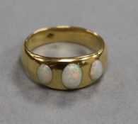 A yellow metal and graduated three stone white opal ring, size L.