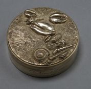 A circular silver box and cover, the latter with sea shells on a stippled and dragged ground,