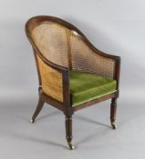 A Regency mahogany bergere library chair, with caned back and seat, on octagonal legs and fitted