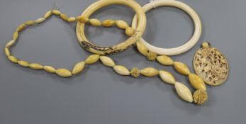 Four pieces of ivory jewellery including two bangles, a necklace and a carved pendant.