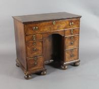 An early 18th century walnut kneehole desk, fitted seven drawers and a cupboard, W.2ft 10in. D.1ft