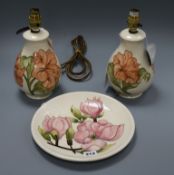 A pair of Moorcroft Hibiscus pattern table lamps and a Magnolia pattern plate, both decorated with