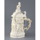 A mid 19th century German ivory tankard, carved with a procession of bacchanalian figures, putti and