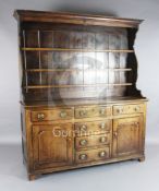 A George III oak dresser, with three shelf rack, six drawers and two panelled doors, W.5ft 10in. D.