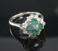 An 18ct white and yellow gold, emerald and diamond cluster ring, claw set with four emeralds and