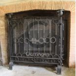 A large wrought iron scrollwork and wire mesh chimney piece spark guard, fitted with a pair of doors