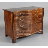 A George III satinwood banded mahogany serpentine commode, the top drawer fitted with a brushing