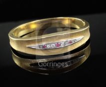 A textured 18ct gold, ruby and diamond set hinged bangle.