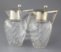 A stylish pair of early 20th century German 800 standard silver mounted wrythened glass claret jugs,
