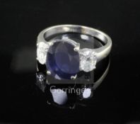 An 18ct white gold sapphire and diamond three stone dress ring, the oval cut sapphire weighing