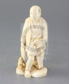 A Japanese ivory okimono of a farmer and two rabbits, early 20th century, one rabbit eating a