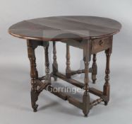 An early 18th century yew wood gateleg table, with oval top and frieze drawer, on turned