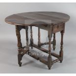 An early 18th century yew wood gateleg table, with oval top and frieze drawer, on turned