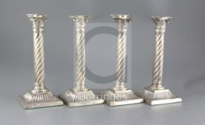 A set of four Victorian silver wrythen pillar candlesticks, with engraved crest, on square bases,