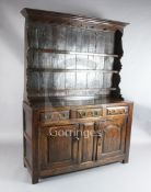 A George III oak dresser, the raised open shelf back with arched frieze and shaped sides, on fielded