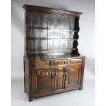 A George III oak dresser, the raised open shelf back with arched frieze and shaped sides, on fielded