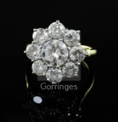 An 18ct gold and nine stone diamond cluster ring, the central round brilliant cut stone weighing