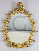 A Victorian carved giltwood wall mirror, with oval plate and ornate floral scroll frame, W.2ft
