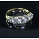 A gold and graduated five stone diamond ring, with carved setting and diamond chip spacers (one