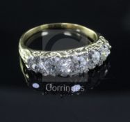 A gold and graduated five stone diamond ring, with carved setting and diamond chip spacers (one