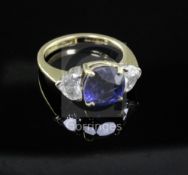 An 18ct gold, synthetic sapphire and heart shaped diamond ring, the central stone flanked by two