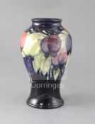 A Moorcroft wisteria baluster vase, decorated with trailing wisteria on a dark blue ground, blue W