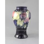 A Moorcroft wisteria baluster vase, decorated with trailing wisteria on a dark blue ground, blue W