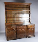 A mid 18th century oak inverse breakfront dresser, with two shelf rack, six long drawers and