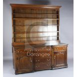 A mid 18th century oak inverse breakfront dresser, with two shelf rack, six long drawers and