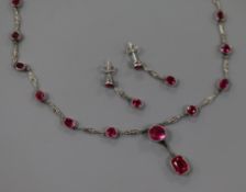 A suite of white metal and synthetic ruby set jewellery comprising a spectacle set drop pendant