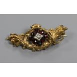 A late Victorian, yellow metal, garnet and pearl scroll brooch, 52mm.