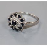 A modern 18ct white gold, sapphire and diamond cluster dress ring, size S.