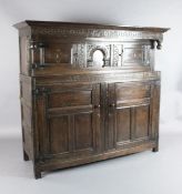 A 17th century oak court cupboard, the frieze carved GBM 1673, with four panelled doors and stile