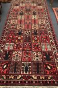 A Baktiari brick red ground rug 360 x 152cm