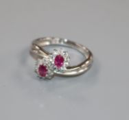 A modern 18ct white gold, ruby and diamond double cluster crossover ring, size M.