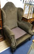 A pair of wing back armchairs, upholstered in brown dralon (lacking cushions)